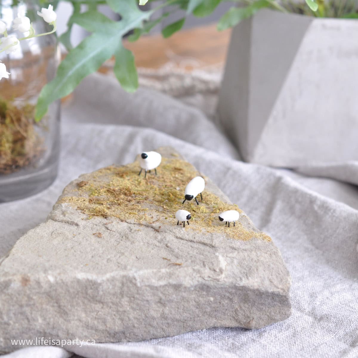 DIY miniature polymer clay sheet on a mossy rock.