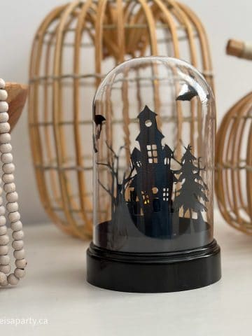 DIY Cricut Halloween Cloche: use dollar store materials to make this haunted house, and graveyard silhouette cloche for Halloween.
